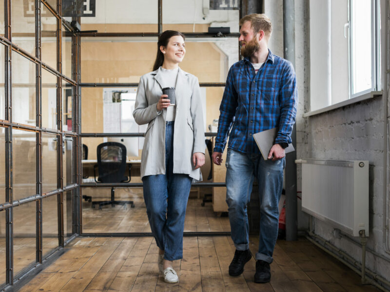 two-young-businesspeople-walking-together-office